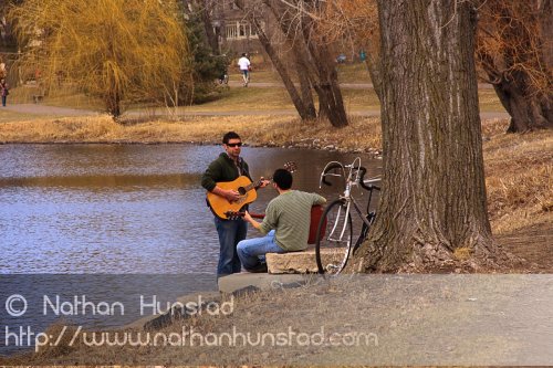 Two guitar players around Lake of the Isles.